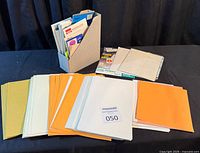 Front view of lot showing coloured paper stacks, magazine file holder and additional stationery items
