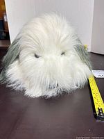 Front view of plush dog head and fur texture with measuring tape visible