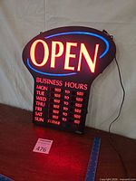 Front view of illuminated LED OPEN sign showing business hours grid