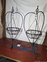 Two identical wrought iron standing planters on table