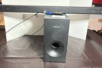 Soundbar positioned on top of subwoofer with remote visible