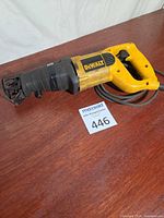 Left side view of DeWalt yellow and black corded reciprocating saw, cord coiled