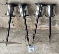 Four solar pathway lights standing against wall showing full height and stakes