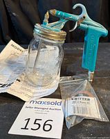 Spray gun attached to jar, repair kit bag and instruction sheet visible