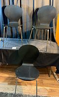 Front view of three stacked black plywood chairs with chrome legs