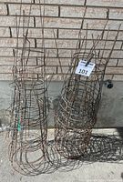 Two stacks of wire tomato cages leaning against wall