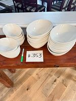 Stacks of large and small white porcelain bowls on wooden table