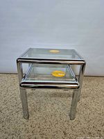 Front view of two chrome and glass nesting tables stacked