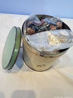 Tin container with lid removed showing bags of buttons inside