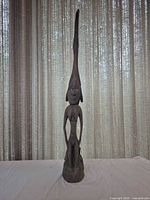 Full front view of tall wooden female figure sculpture
