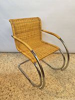 Front angle view showing wicker seat, back, chrome frame, armrests, cantilever base