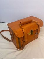 Front and top view of tan leather camera bag with handle, clasp and strap