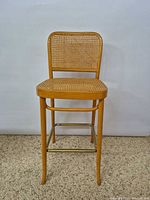 Front view of bar stool showing wood frame and cane seat/back