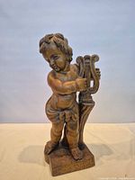Full view of carved wooden cherub figurine standing on rectangular base