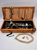 Open wooden jewelry box showing assorted jewelry and items placed in front
