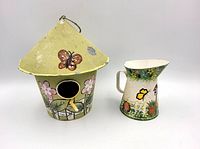 Front view of bird feeder and pitcher showing painted designs and shapes