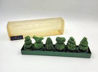Full set of six green topiary candles in tray with lid set behind