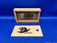 Corkscrew inside open wooden presentation box with slide lid displaying 50 Candiac logo