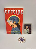 Group shot showing signed Offside book, Manon Rheaume trading card, Brampton Dominion Ladies Hockey Tournament pin