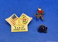 Front view of three hockey lapel pins on blue background