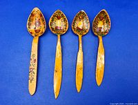 Front view of all four hand-painted spoons on blue background
