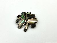 Front view of four-leaf clover brooch showing abalone inlay and silver outlines