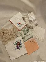 All seven handkerchiefs laid out to show embroidery, lace trims and colors