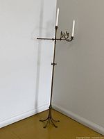 Full view of tall brass floor candelabra with two candles inserted, showing height and base