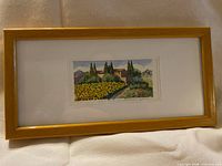Full view of framed watercolor in golden wood frame