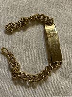 Full view of gold-tone curb chain bracelet with ID plate