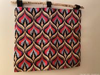 Front view of entire Bargello tapestry hanging on wall with wood rod and black loops.