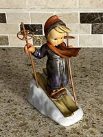 Front angle of porcelain skier boy figurine on skis with metal poles