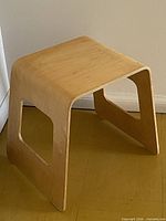 Three-quarter view of stool showing bent plywood form and cut-out sides