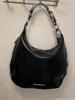 Full view of front of black leather hobo bag hanging on hook