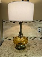 Full view of lamp with shade illuminated on countertop