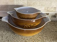 Three amber Pyrex nesting bowls side view showing decal