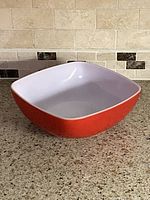 Angled view of Pyrex square red exterior white interior baking dish