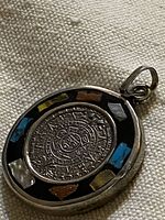 Pendant front showing Aztec calendar center with surrounding stone inlay
