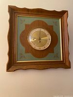 Front view of square wood-framed Turner wall clock showing dial and design