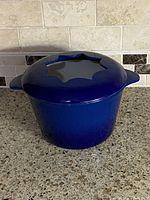 Front view of blue enameled cast iron fondue pot with star-cut lid