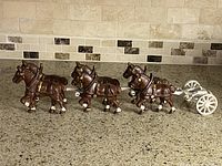 Full view of six horses hitched to white wagon frame on countertop