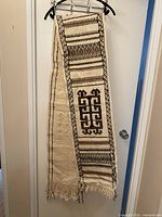 Full view of folded Fulani wool runner hanging, showing overall pattern and fringe