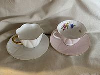 Both teacup and saucer sets displayed side by side