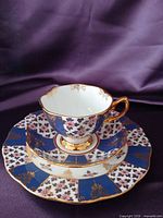 Front view of teacup on saucer and dessert plate displaying pattern and gilt