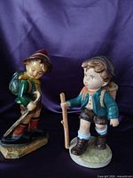 Front view of both ceramic boy hiker figurines
