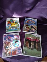 Group shot of all four Wii game cases on purple fabric