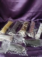 Eight individually packaged fabric catnip stick toys displayed on purple cloth