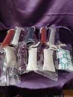 Group view of ten individually wrapped catnip pouch toys on purple cloth