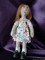 Full view of 15-inch cloth doll standing against purple backdrop