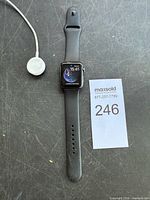 Apple Watch laid flat with magnetic charger and lot card visible